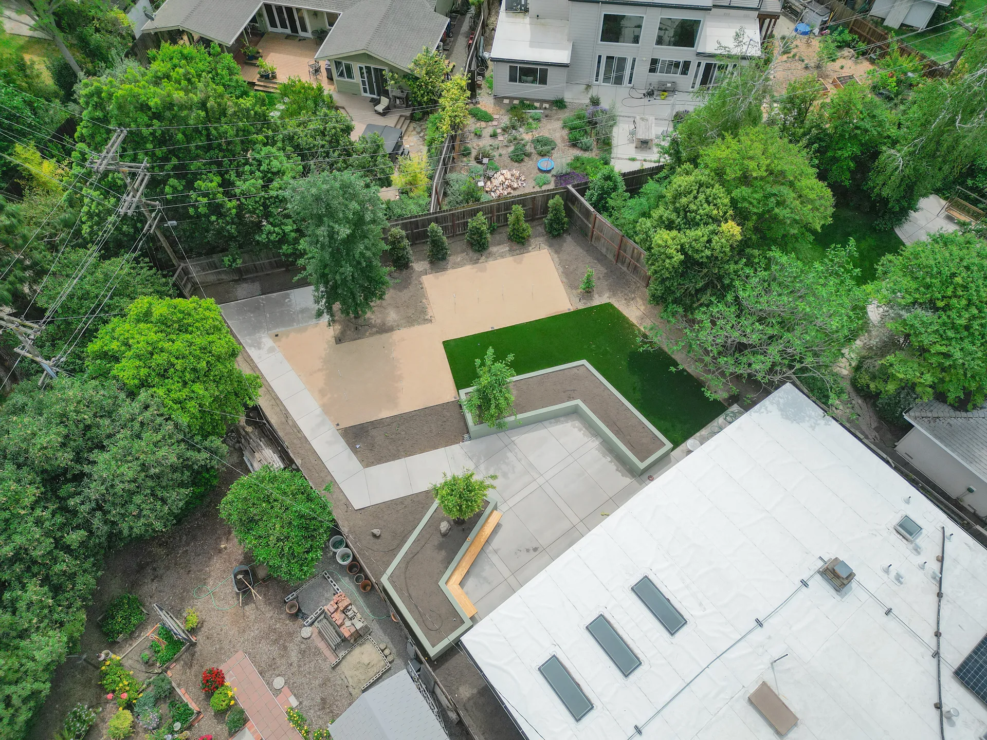 Aerial view of backyard hardscape construction with concrete patio, turf, and tree planting in Sacramento