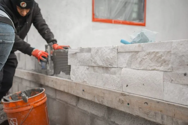 Stuteville Landscaping crew installing natural stone veneer on a retaining wall in Sacramento