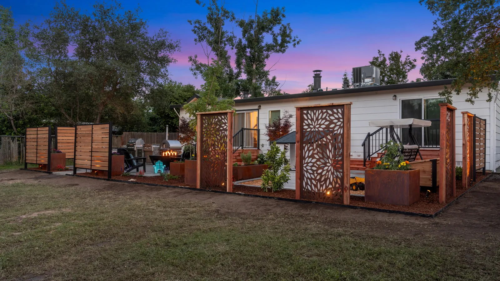 Backyard fire features and lit privacy screens at dusk on a recent Sacramento project