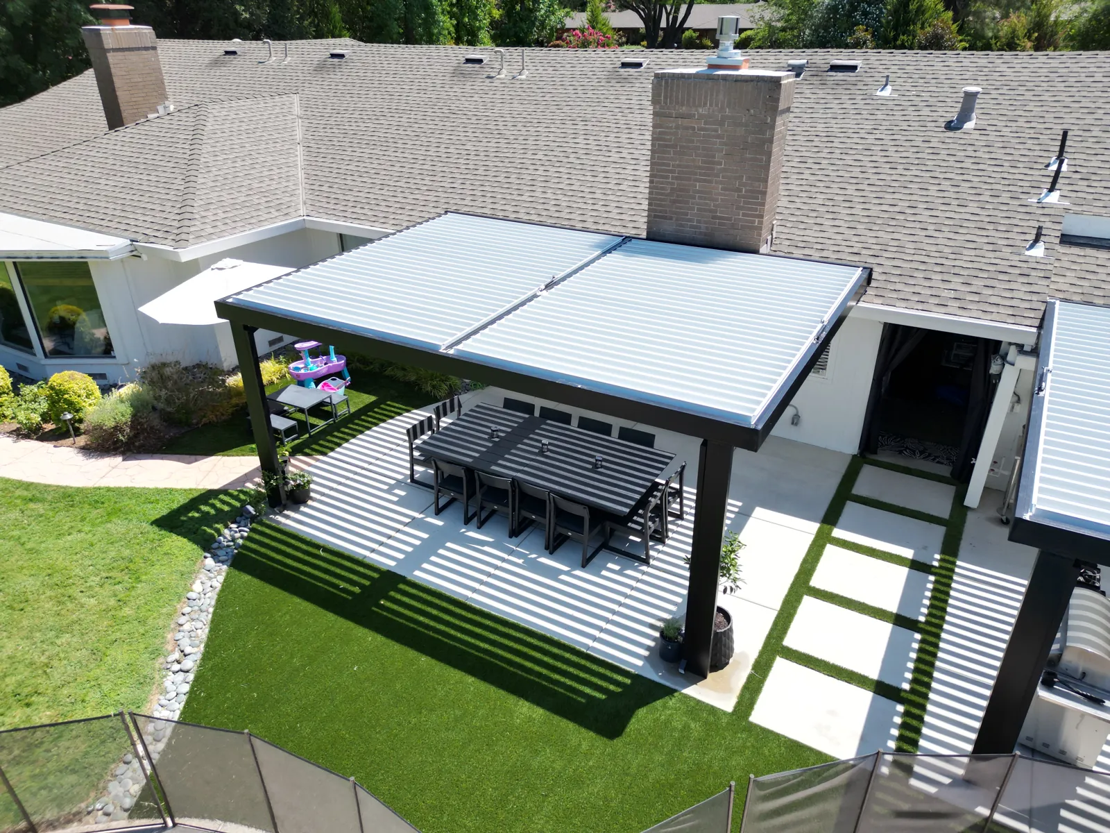 Aerial view of a louvered pergola roof with paver and turf bands in a Sacramento backyard